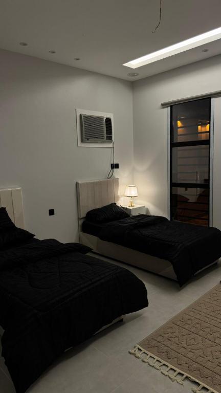 a bedroom with two beds and a tv on the wall at شاليه in Al Baha