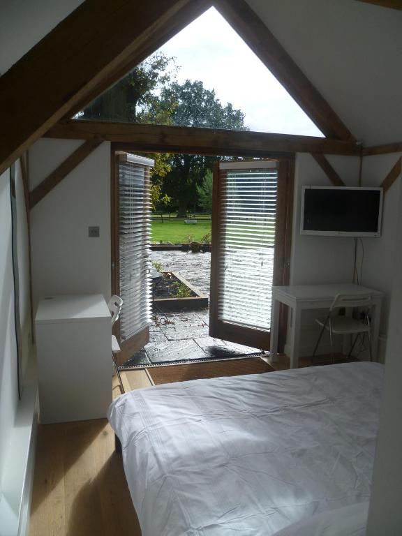 a bedroom with a bed and a large window at Little Oak - Small Rural Self Contained Oak Barn Unit - Sleeps 2 in Haslemere