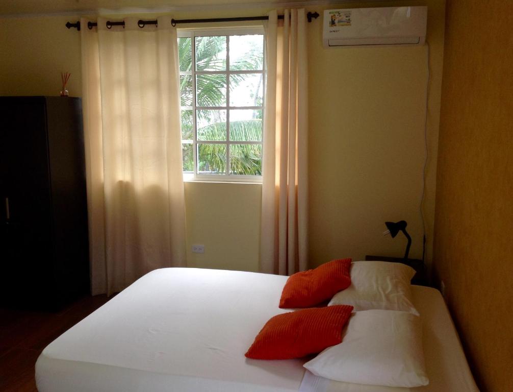uma cama com almofadas vermelhas e brancas em frente a uma janela em Honey Hill View em San Andrés