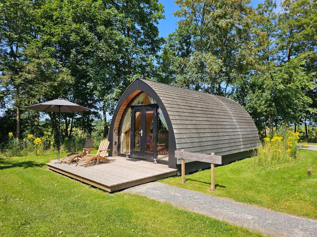 a small cabin in the grass with an umbrella at Tiny House De Bosksjonger in Westergeest