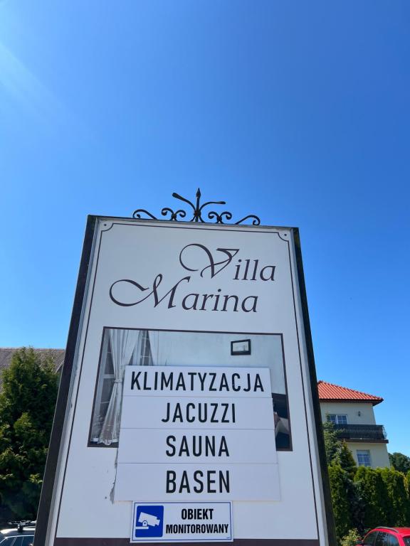 a sign for a restaurant in a parking lot at Villa Marina in Dąbki