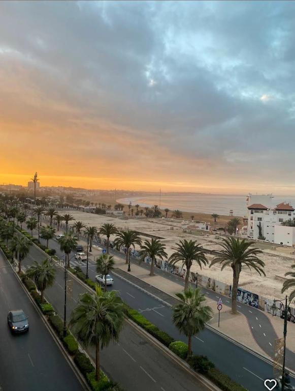 a city street with palm trees and the beach at Couzi Haus Marina in Agadir