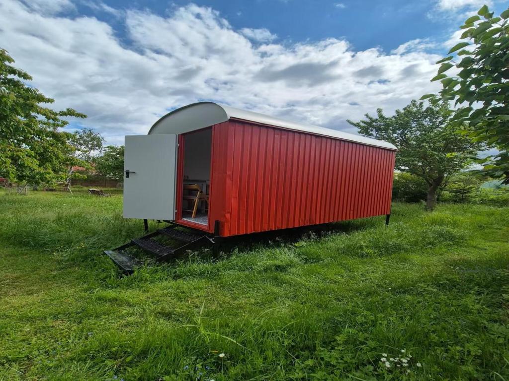 a red shed sitting in a field of grass at Gemütlicher Rustikaler Bauwagen in Vippachedelhausen