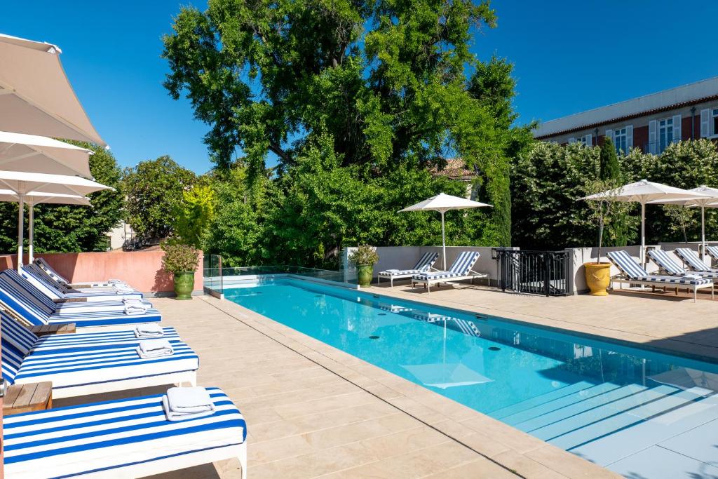 a swimming pool with lounge chairs and umbrellas at Maison Albar Hotels L’Imperator in Nîmes
