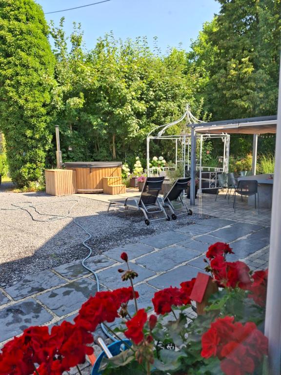 a patio with chairs and red flowers in the foreground at Label Semois-L'Orée des sens-Bain nordique privé in Bouillon