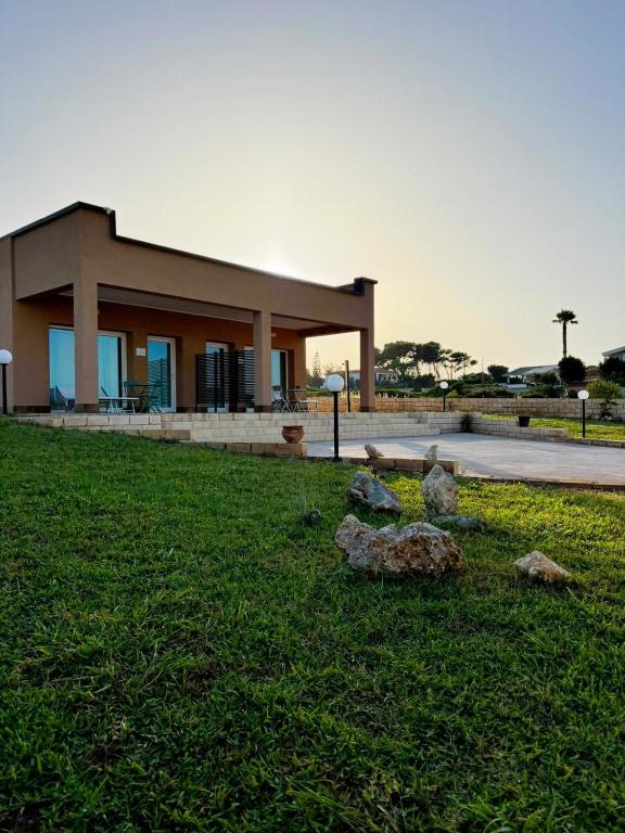 a building with rocks in the grass in front of it at Plemmirio Marèa in Plemmirio