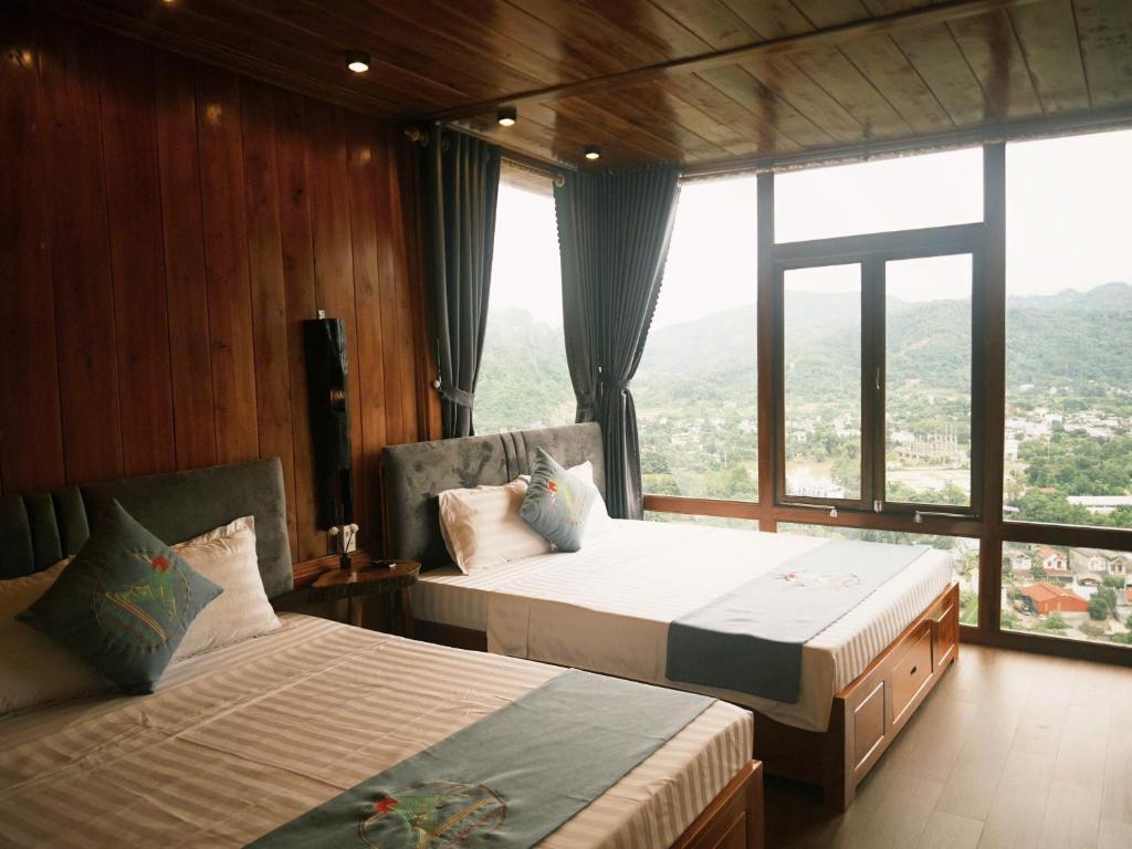 two beds in a room with a large window at HagiangHillside in Ha Giang