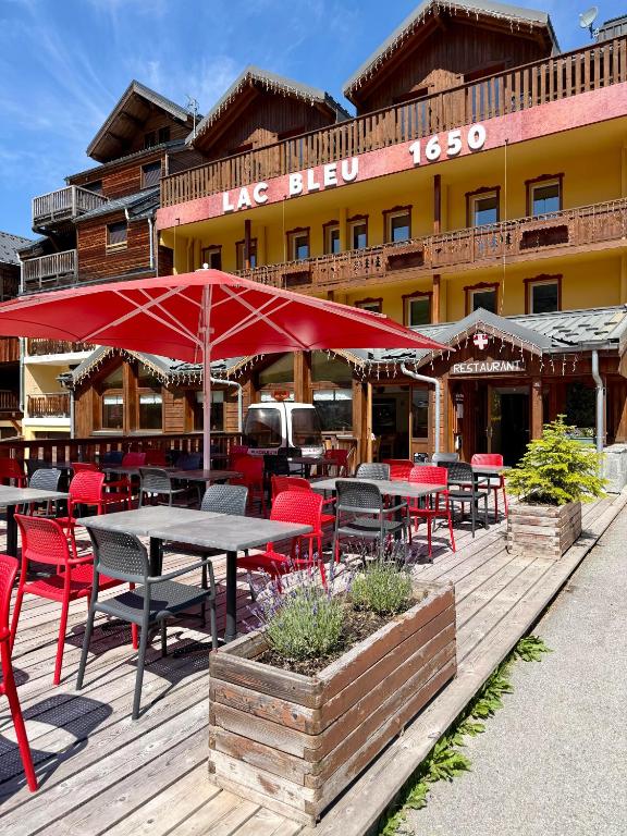 a restaurant with tables and chairs and red umbrellas at Hotel Lac Bleu 1650 in Saint-François-Longchamp