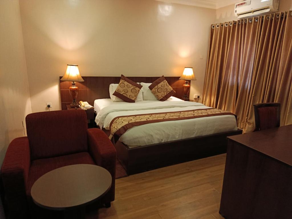 a hotel room with a bed and a chair at Grand Inn & Suites in Ijebu Ode