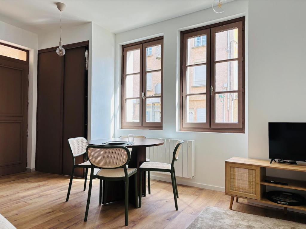 a dining room with a table and chairs and windows at La Halte Beaujolaise in Belleville-en-Beaujolais