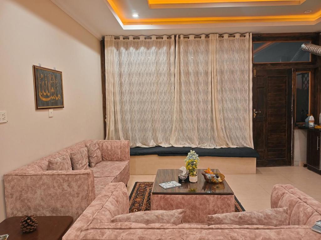 a living room with two couches and a table at Sunset View Luxury Apartments in Nathia Gali