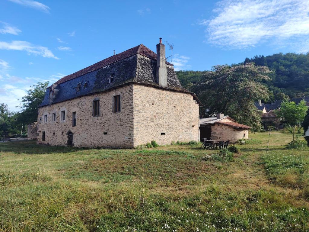an old building with a chimney on top of a field at Lo Castel de Lasmaries in Saint-Parthem