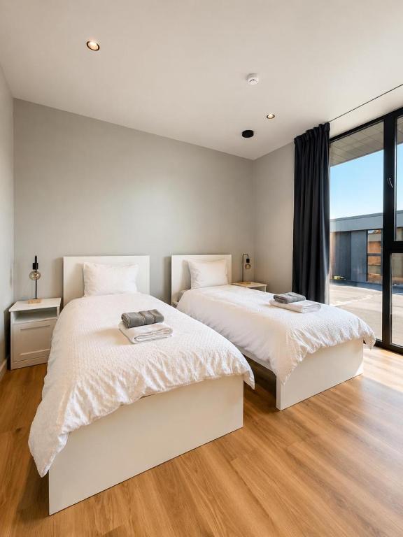 a white bedroom with two beds and a window at Green Guest House in Sigulda
