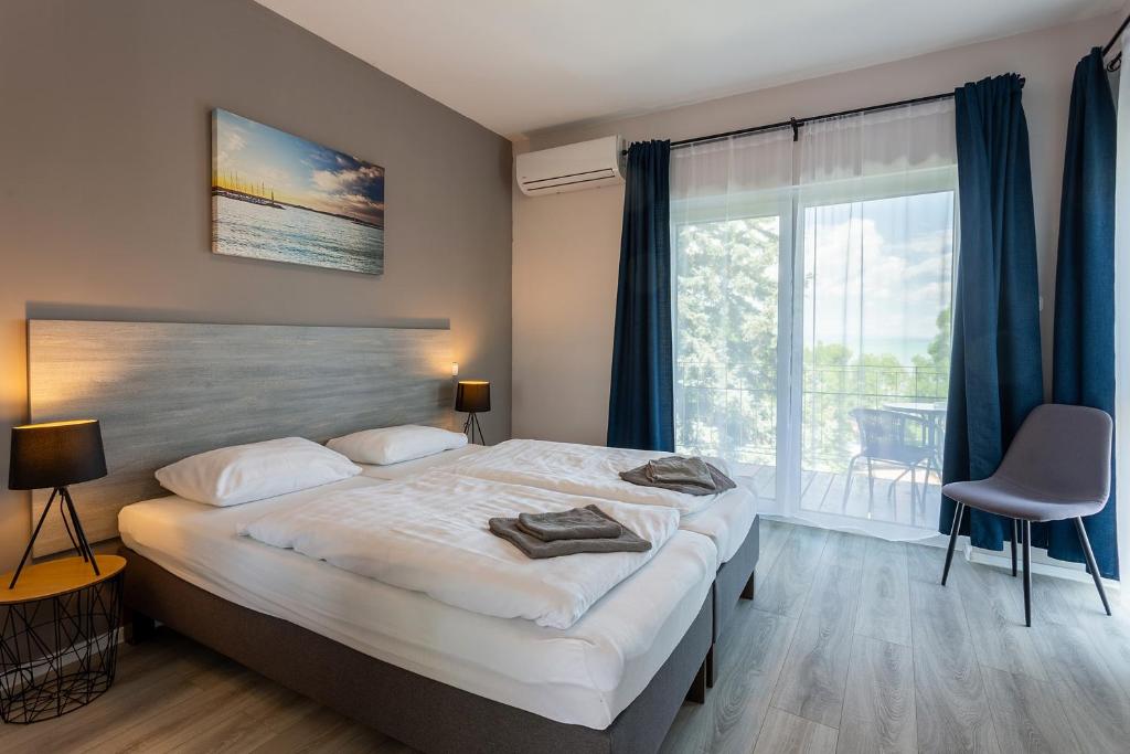 a bedroom with a large bed and a large window at Holiday Hotel Siófok in Siófok