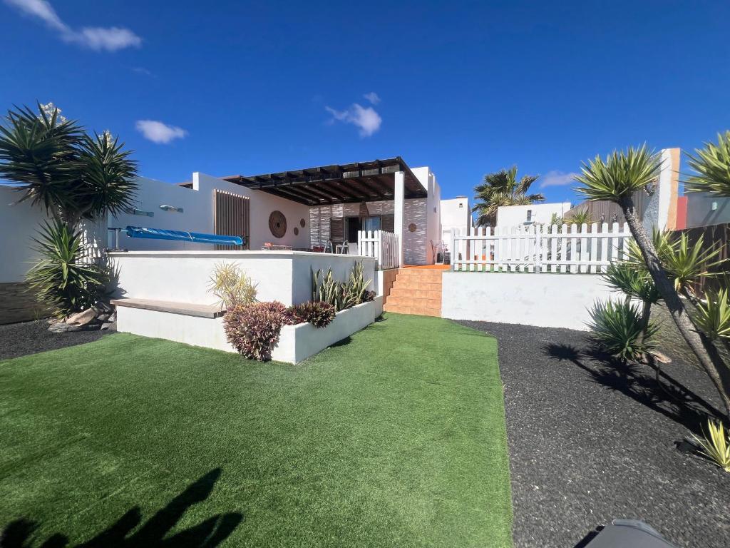 a backyard with a white fence and green grass at Villa Dinateli, Salinas Golf in Caleta De Fuste
