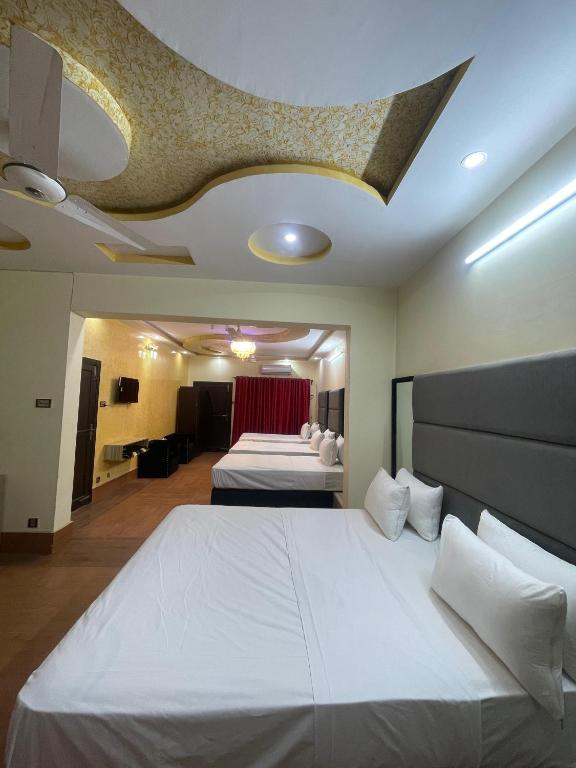 a hotel room with two beds and a ceiling at Aban Guest House in Peshawar