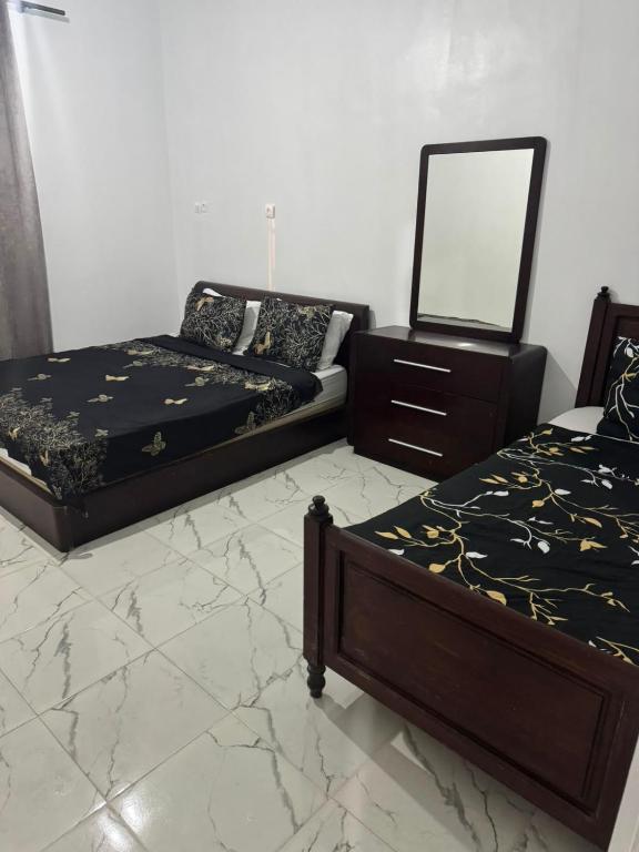 two beds in a room with a mirror and a dresser at maison soleil in Nouaceur