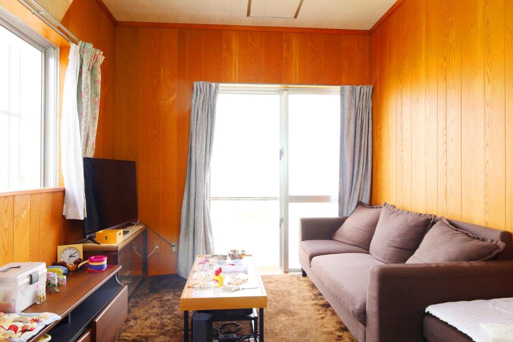 ein Wohnzimmer mit Sofa und Fenster in der Unterkunft アトムハウス in Okinawa