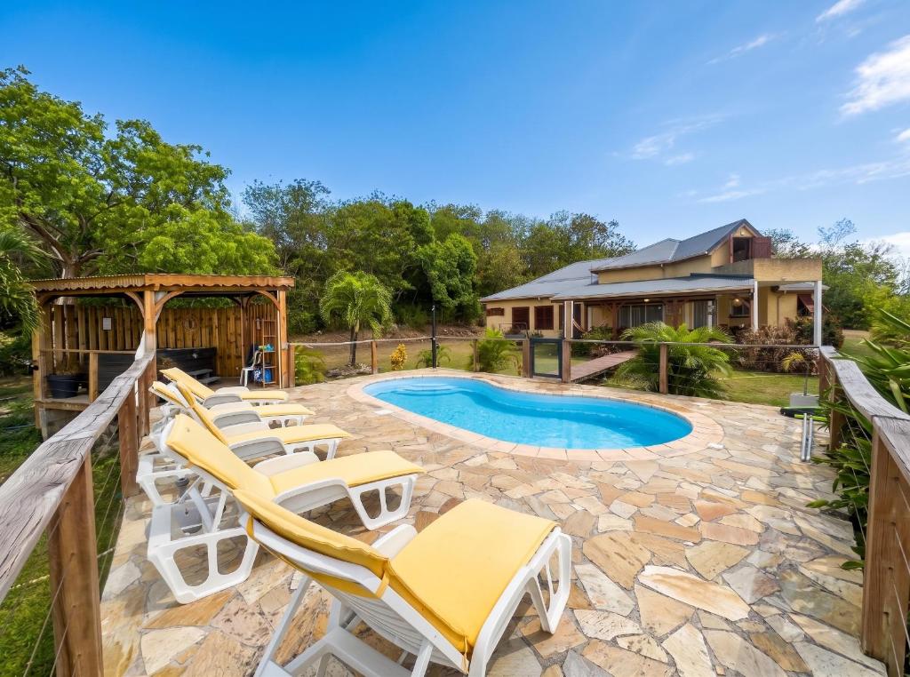 a patio with lounge chairs and a pool at Maison conviviale à Deshaies avec piscine partagée 120 m² in Deshaies