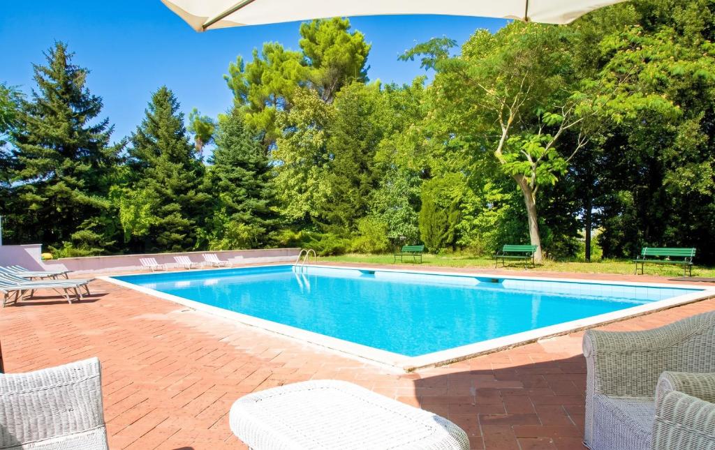 a swimming pool with chairs and an umbrella at Comfortable Apartment in Fabriano, 35 m² with Shared Pool in Fabriano