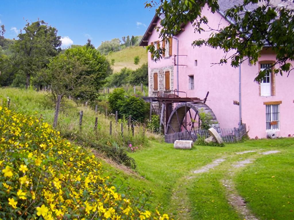 a pink house with a mill next to a field of flowers at Maison charmante à Chirens avec jardin clôturé in Chirens