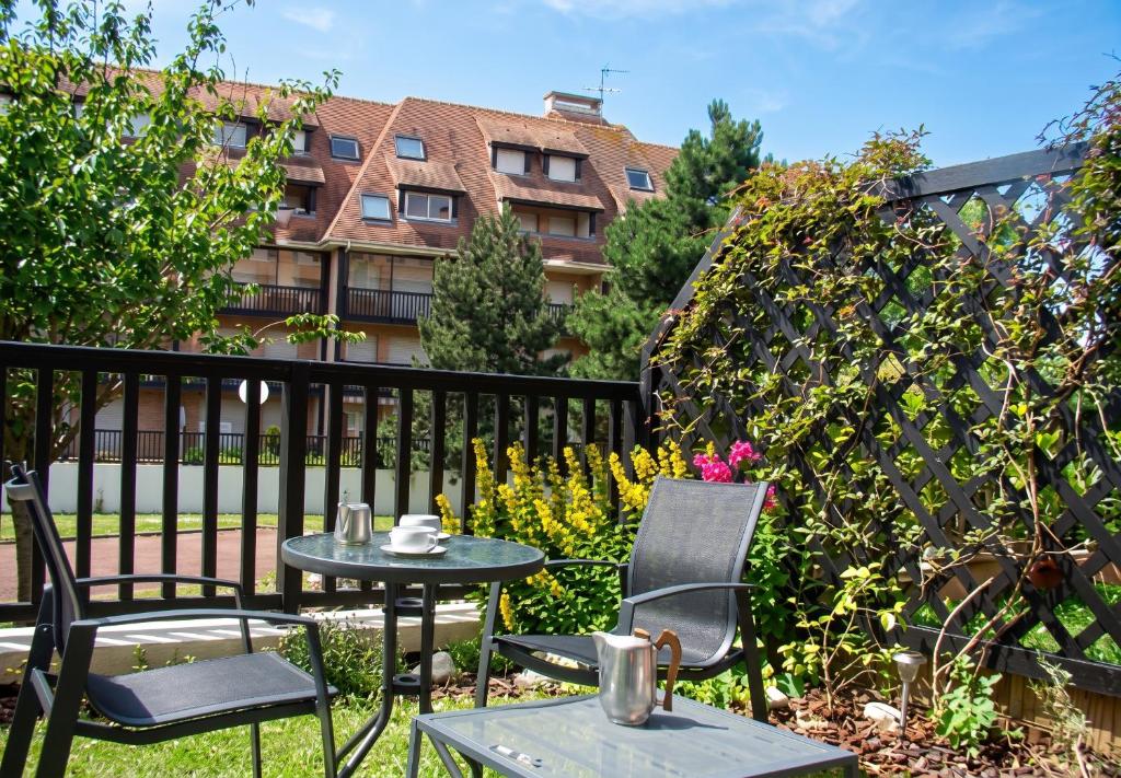 two chairs and a table in a yard with a fence at Studio charmant à Villers-sur-Mer avec terrasse - 33 m² in Villers-sur-Mer