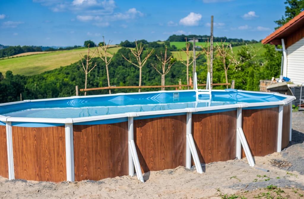 a pool with a wooden wall and a blue swimming pool at Charmante maison avec piscine privée à Orsanco - 70 m² in Orsanco