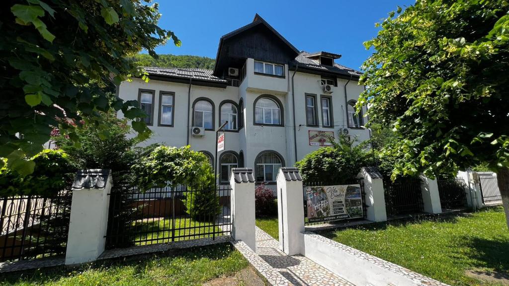 a white house with a fence in front of it at Vila Crinilor Căciulata in Căciulata