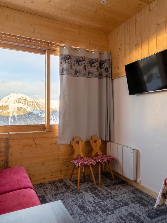 a room with a couch and a tv and a window at Studio chaleureux à Aime la Plagne 25 m² en montagne in Aime-La Plagne