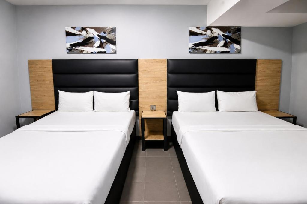 two beds in a small room with two paintings on the wall at Hotel Metro Lodge Beach in Durban