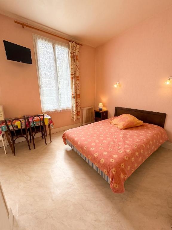 a bedroom with a bed and a table and a window at Studio confort à Néris-les-Bains - 18 m² avec jardin in Néris-les-Bains