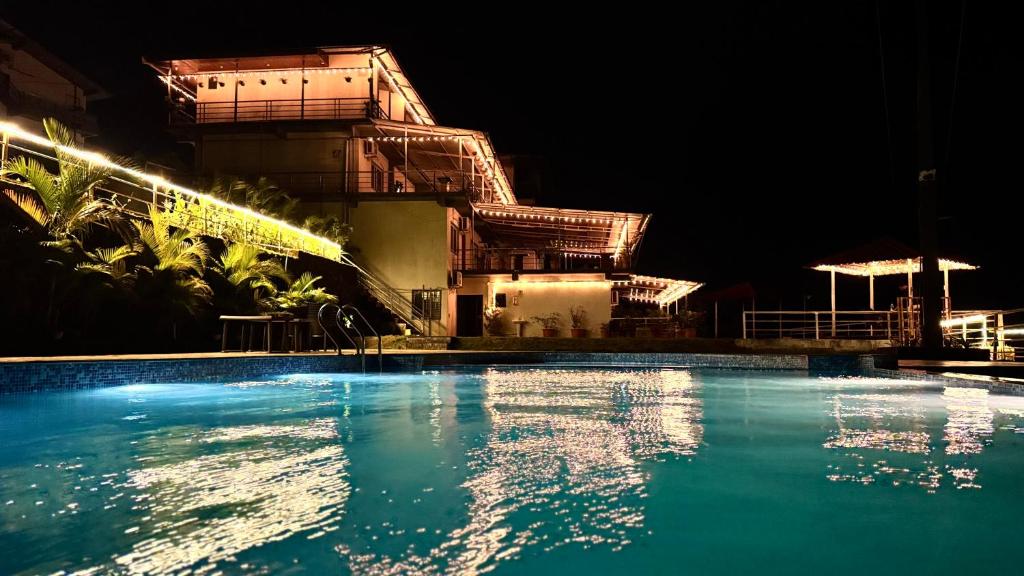 a swimming pool in front of a building at night at Nature's Glory Resort in Panchgani