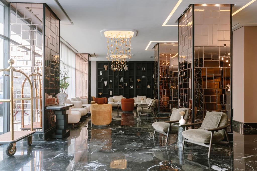 a lobby with chairs and tables and a chandelier at Occidental Casablanca Medina in Casablanca