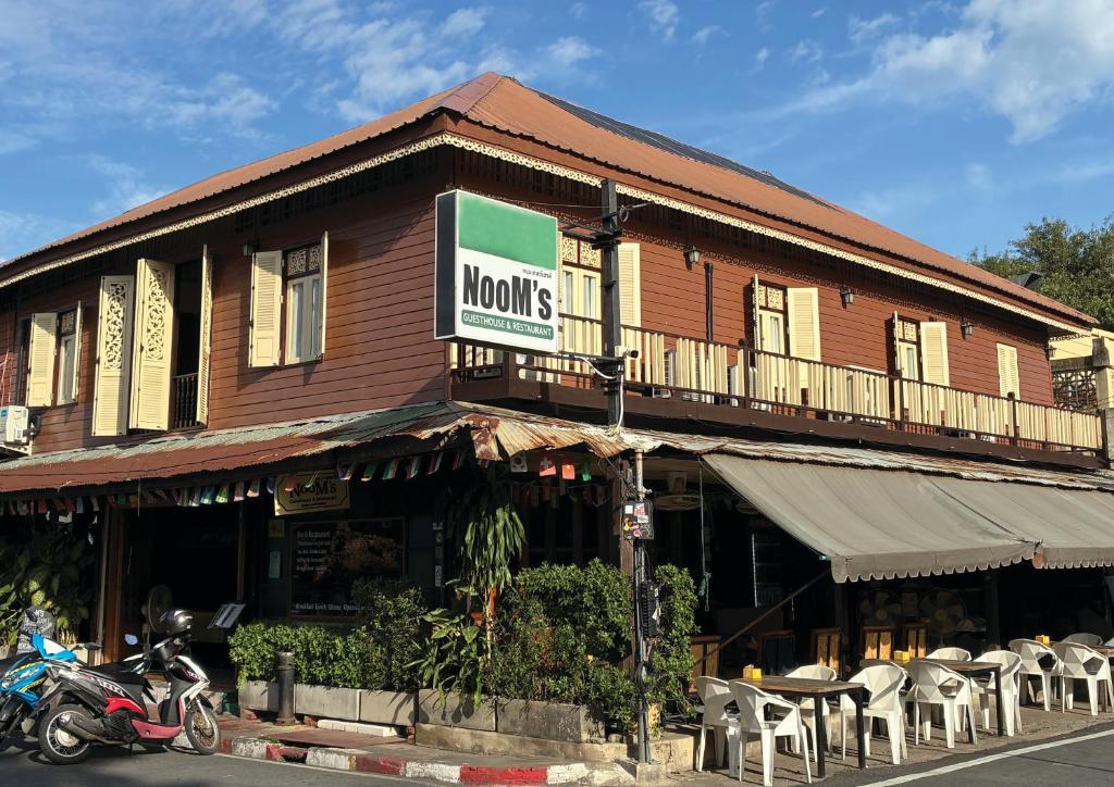 a building with a sign on the side of it at Noom Guesthouse in Lop Buri