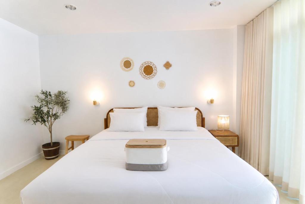 a bedroom with a large white bed with a table on it at Beachfront Pool Access Apartment FREE Disney Plus in Bangsaen
