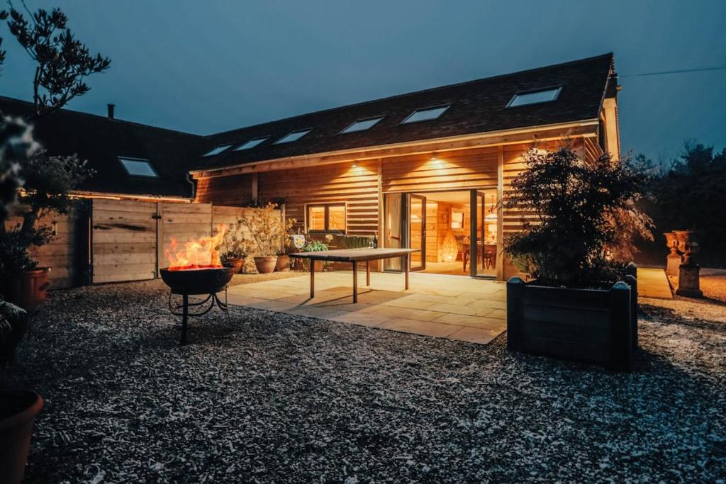 a house with a patio with a table in front of it at Owl Barn in Little Milton