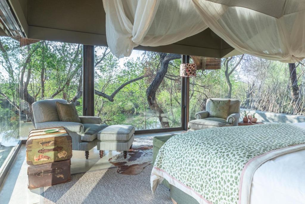 a bedroom with a bed and chairs and a window at Last Word Makanyane in Laastepoort