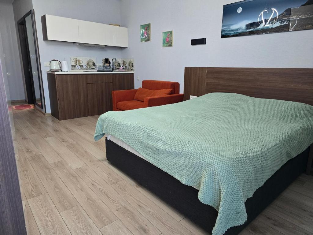 a bedroom with a bed and an orange chair at Cozy Ski-In Studio near forest at Crystal residence in Bakuriani