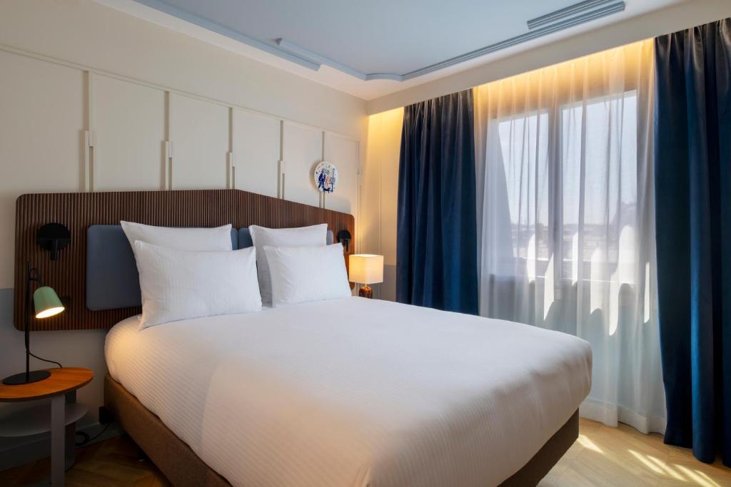 a bedroom with a large white bed and a window at Urban Hive Paris in Paris