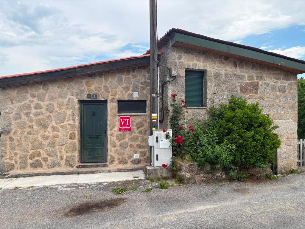 a stone house with a green door and a refrigerator at Cabana do Sil in Forcas