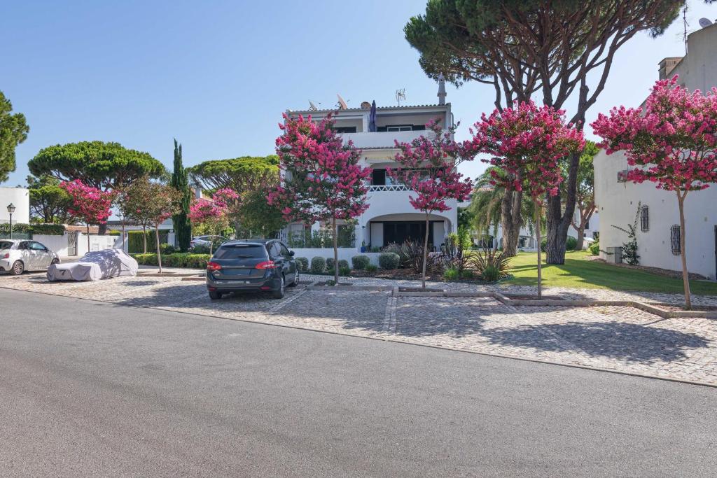 a car parked in front of a house with pink flowering trees at Bia in Almancil