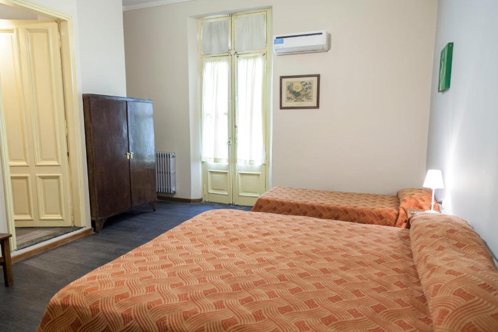 een hotelkamer met 2 bedden en een kast bij Hotel Reina in Buenos Aires