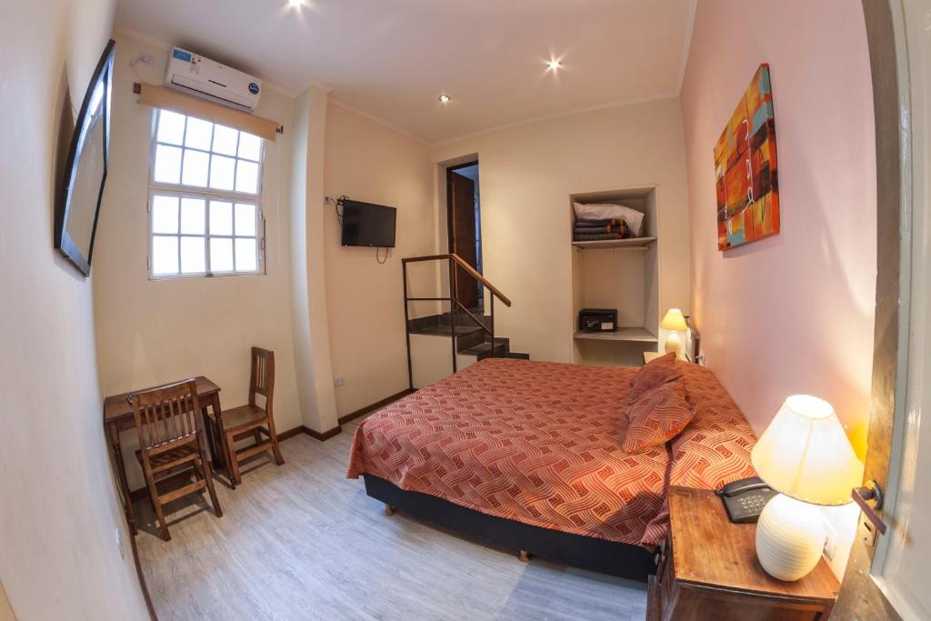 a bedroom with a bed and a desk and a window at Hotel Reina in Buenos Aires