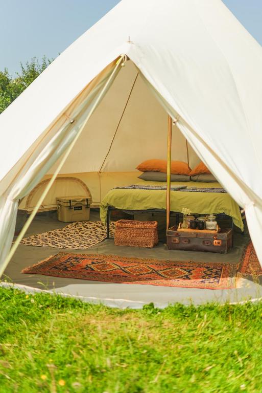 a white tent with a bed and luggage inside at Devon Belltents - Beesands in Kingsbridge