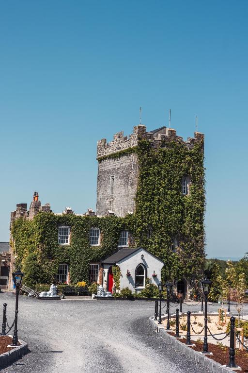an ivycovered castle with a white house in front at Cloonacauneen Castle in Galway