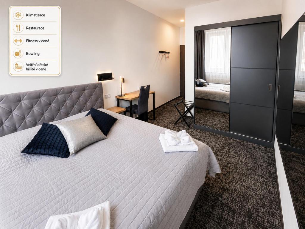 a bedroom with a large bed and a desk at Olympland Hotel in Trutnov