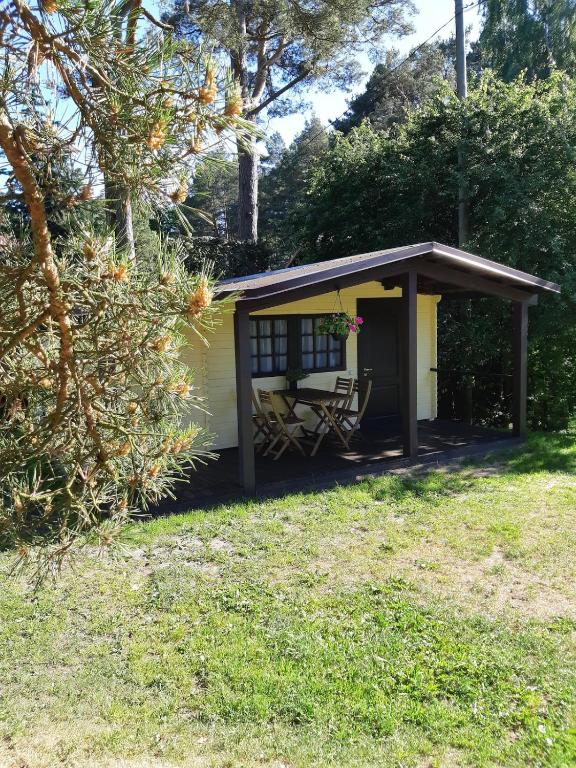 a shed with a table and a chair in a yard at Cozy house for your holidays in Bernāti