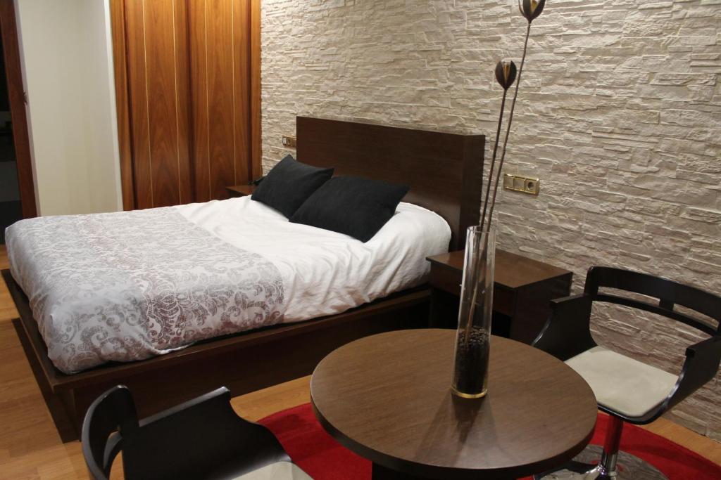 a bedroom with a bed and a table and chairs at Hotel El Castillo in Ponferrada