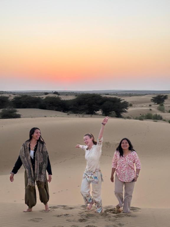 three women walking in the sand in the desert at Jaisalmer Hostel Camel Castle & Safari in Jaisalmer