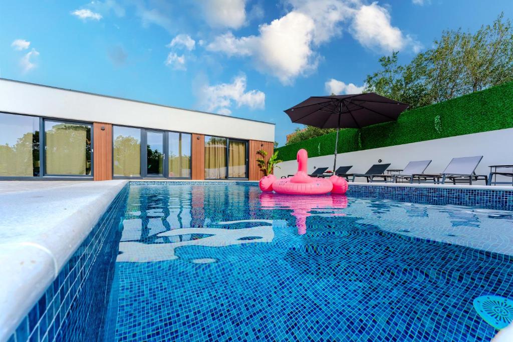 an infinity swimming pool with an inflatable raft and an umbrella at Villa Sunshine in Pridraga